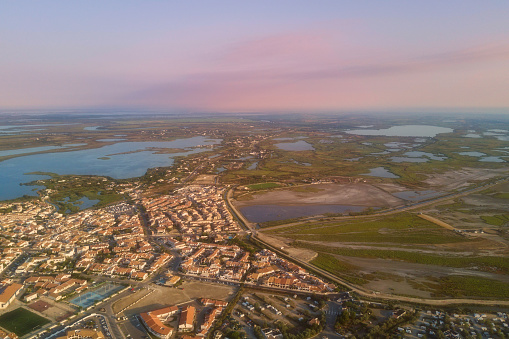 Aerial view of Saintes-Maries-de-la-Mer and wetland of Camargue reserve at sunset, panoramic landscape, Provence, France