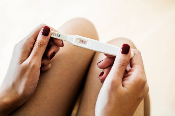 istock Woman holding a positive pregnancy test 1067759622