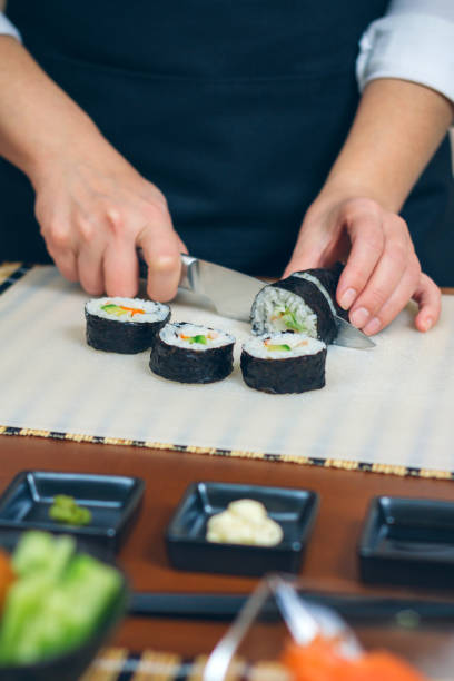 istock Female chef cutting japanese sushi roll 1067764914