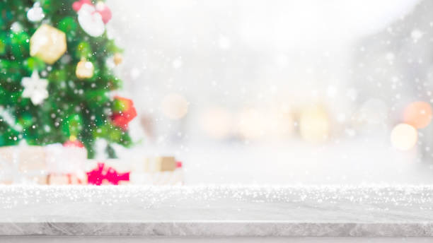 istock Empty white marble stone table top with bokeh light on blurred Christmas tree banner background with snowfall - can be used for display or montage your products. 1067768668