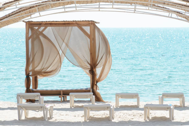 istock Empty beach beds. Lounge chaise on a sand shore,sun umbrellas omission, empty beach, summer 1067770526