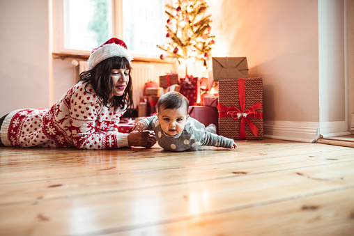 little kid playing with the mother on the parquet floor at christmas