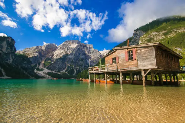 Wonderful summer scenery of Braies Lake (Pragser Wildsee) with wooden hut on shore and colorful trees and mountains on background, Fanes-Sennes-Braies Nature Park, Italy, Europe