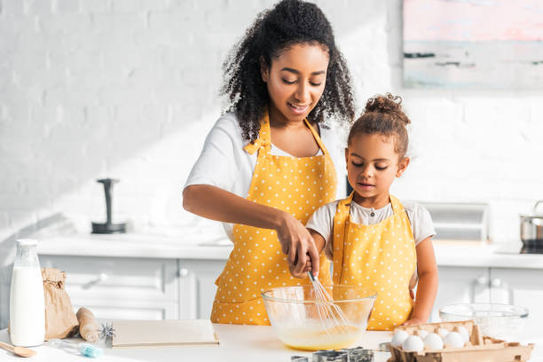 アフリカ系アメリカ人の母と娘の生地を準備して、キッチンで卵を whisking - preschooler child offspring purity ストックフォトと画像