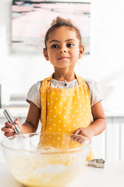 istock adorable african american kid preparing and whisking dough in kitchen 1067784364