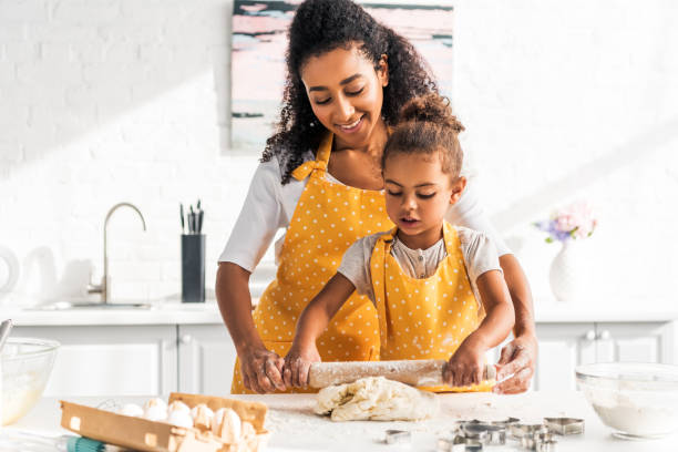 istock african american mother helping daughter rolling dough with rolling pin in kitchen 1067784434