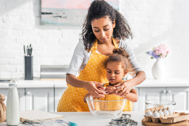 istock african american mother helping daughter breaking egg for preparing dough in kitchen 1067784594