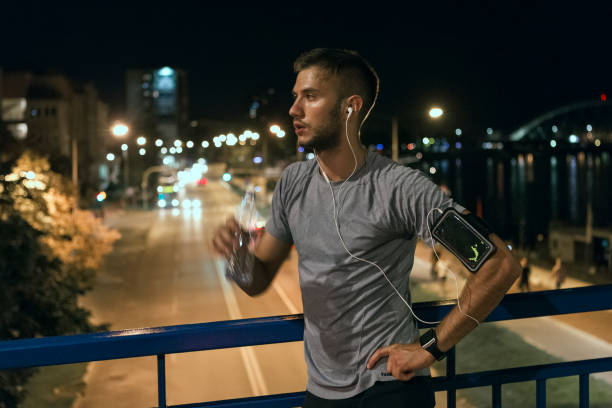 istock Young man drinking resting after jogging through the city at night 1067784890