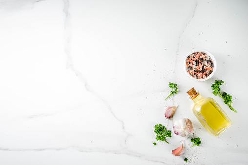 Cooking background with spices, olive oil and herbs, white marble background, copy space top view