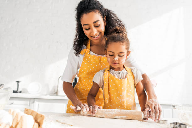 istock smiling african american mother helping daughter rolling dough with rolling pin in kitchen 1067791874