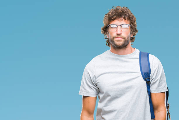 istock Handsome hispanic student man wearing backpack and glasses over isolated background with serious expression on face. Simple and natural looking at the camera. 1067800184