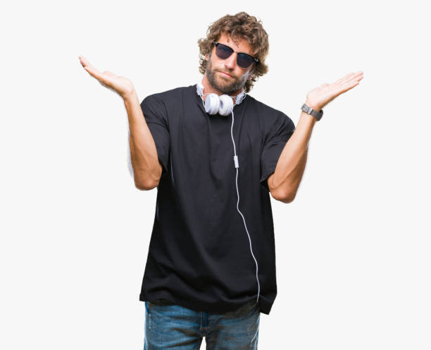 handsome hispanic man listening to music wearing headphones over isolated background clueless and confused expression with arms and hands raised. doubt concept. - head and shoulders audio imagens e fotografias de stock