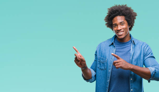 istock Afro american man over isolated background smiling and looking at the camera pointing with two hands and fingers to the side. 1067803432