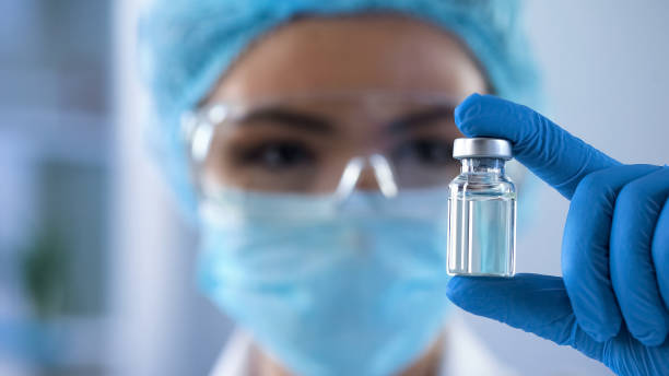 Lady scientist looking at ampoule with new medication, vaccination development stock photo