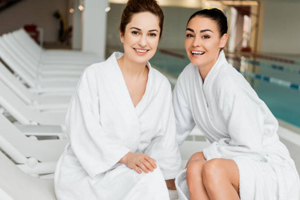 istock happy young women in bathrobes smiling at camera while relaxing together in spa 1067809352