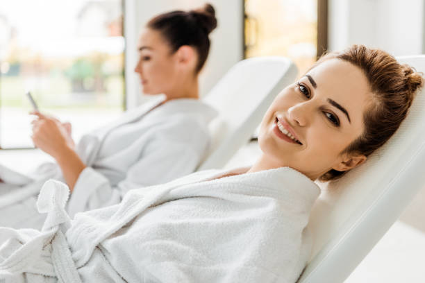 istock happy young oman in bathrobe smiling at camera while resting on sunbed in spa 1067809360