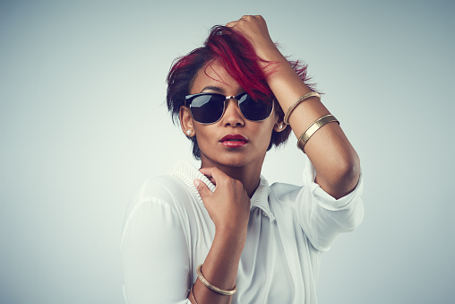 Shot of a beautiful young woman wearing sunglasses against a grey background