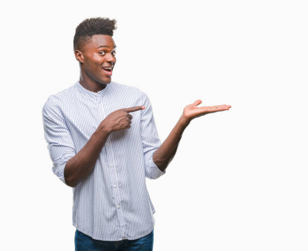 istock Young african american man over isolated background amazed and smiling to the camera while presenting with hand and pointing with finger. 1067815762
