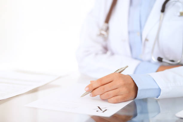 Doctor woman filling up prescription form while sitting at the desk in hospital close-up. Physician at work and ready to give an advice to help patient. Healthcare, insurance and excellent service in medicine concept. médico mujer llenando formulario de recetas mientras estaba sentado en la mesa en primer plano del hospital. médico en el trabajo y listos para dar un consejo para ayudar a la paciente. salud, seguro y excelente servicio en concepto de medicina.