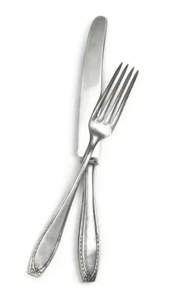 Vintage cutlery, silverware. Old silver cutlery, isolated on white background. Top view of table knife and fork with ornament details.