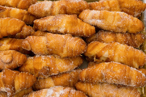 istock Bunch of freshly baked delicious deep fried croissants cronuts dusted with sugar. Appetizing golden crust. American pastry. Baking unhealthy diet concept 1067817266