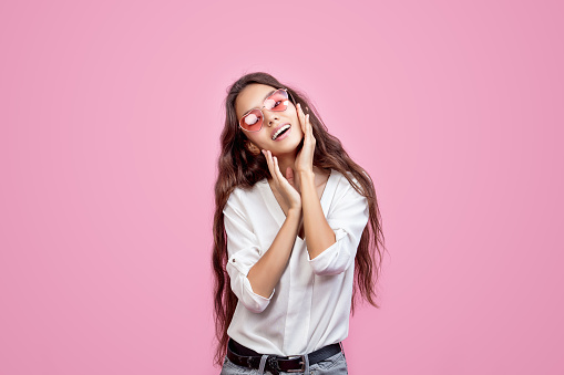 Model young fashionable beautiful girl with natural makeup and pink glasses on pink background fashionable Studio shot