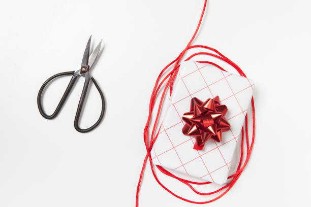 istock Beautiful white red gift box, scissors and red tape on white background. Flat lay, top view 1067826682