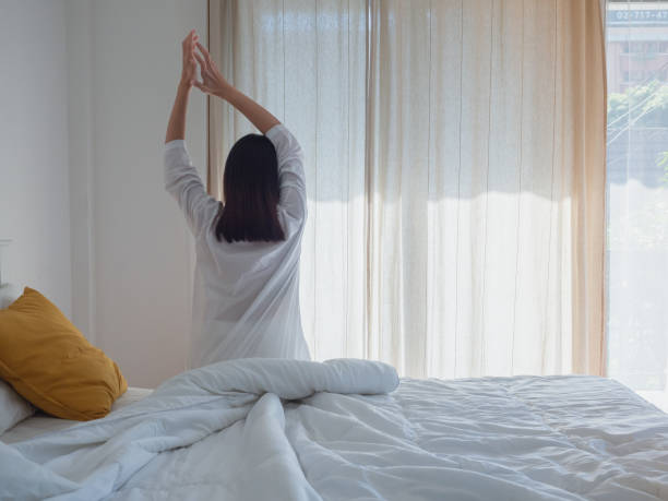 istock asian woman stretching in bed after wake up 1067832184
