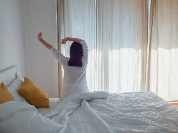 istock asian woman stretching in bed after wake up 1067832378