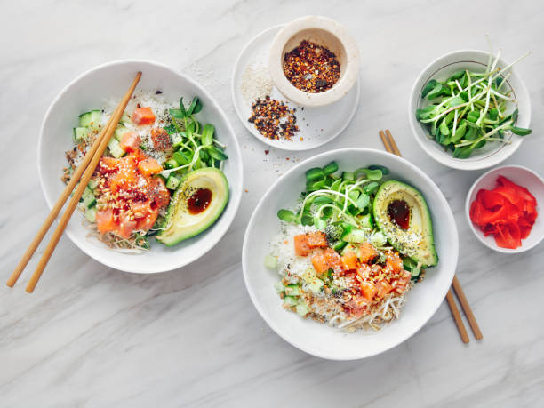 Poke bowls with ponzu dressing Poke bowls with salmon, avocado, vegetables, sprouts and ponzu dressing on marble background seafood salad stock pictures, royalty-free photos & images