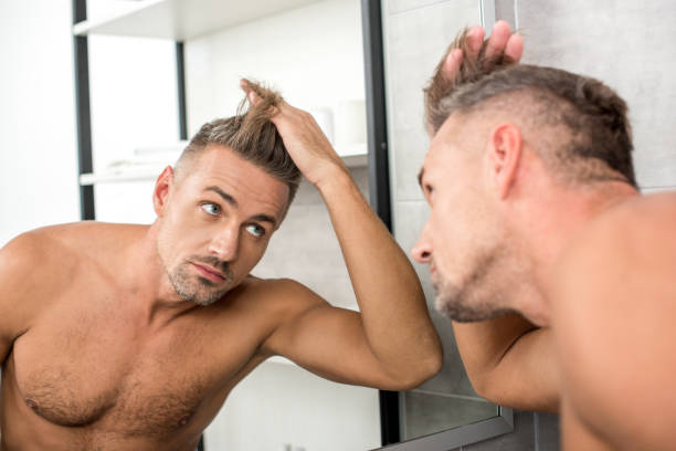 istock adult man adjusting haircut while looking at mirror in bathroom 1067850860