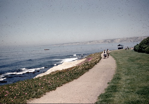 La Jolla, United States - January 01, 1965:  Two women are visible in the distance walking a baby carriage along the shoreline of the Pacific Ocean in La Jolla, California, 1965