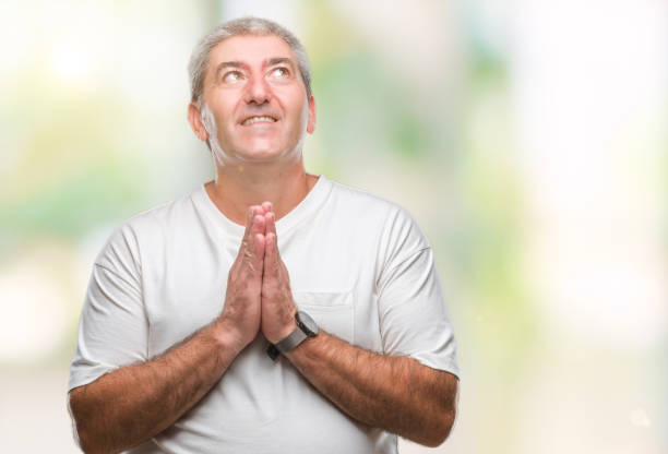 istock Handsome senior man over isolated background praying with hands together asking for forgiveness smiling confident. 1067861918