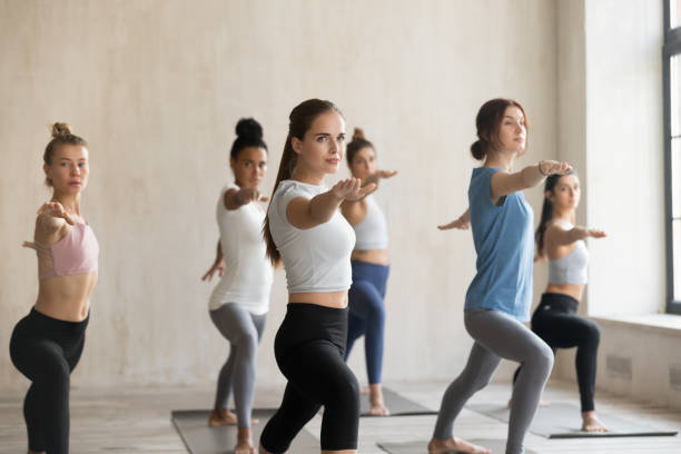 istock Group of young people practicing yoga lesson, Warrior II pose 1067864366