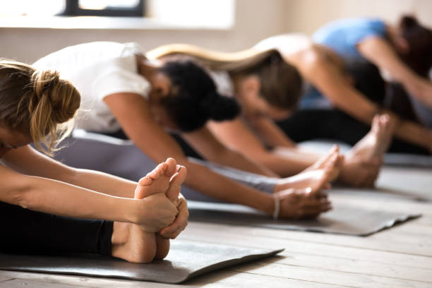 istock Group of women practicing yoga, Seated forward bend exercise 1067864586