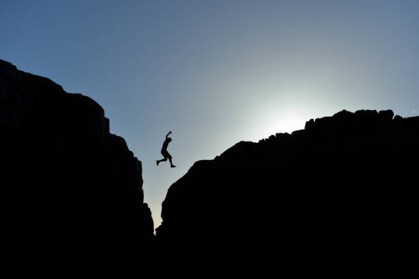 istock man who jumped on the rocks in silhouette 1067872582