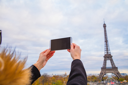 Girl using cellphone with Paris city background and Eiffel tower.