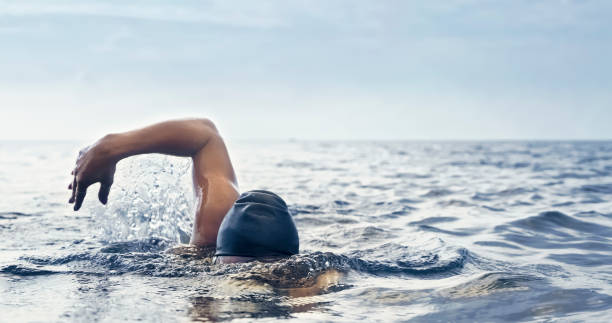 nuotatore in acque libere che nuota in mare - splashing color image front view head and shoulders foto e immagini stock