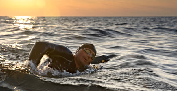 istock Male swimmer swimming front crawl in sunset 1067877496