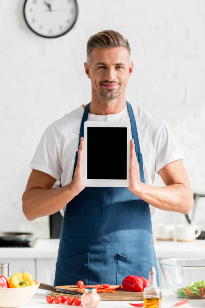 istock adult man holding digital tablet with blank screen at kitchen 1067883560