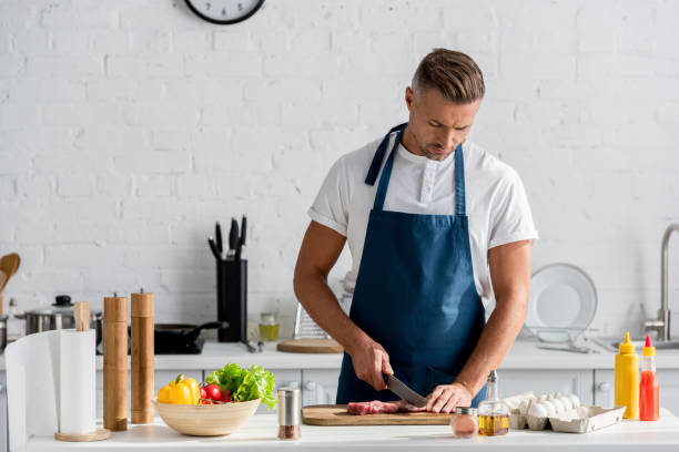 istock Mature man cutting meat for dinner in kitchen 1067883802