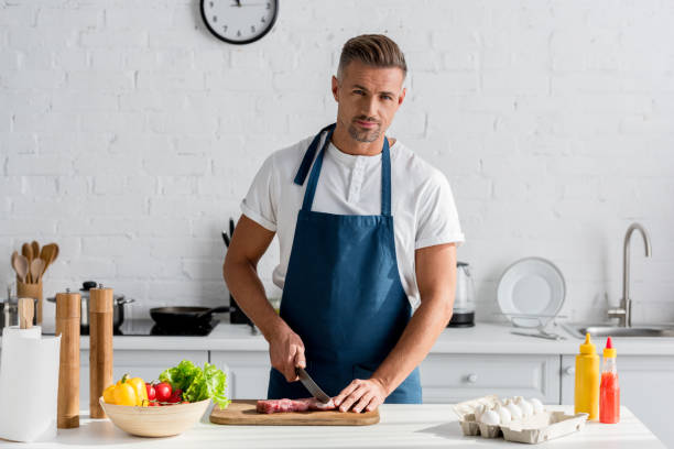 istock handsome man cutting pork meat on the kitchen 1067883818