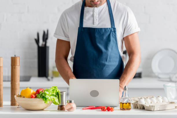 istock cropped view of man in apron working on laptop at kitchen 1067884942