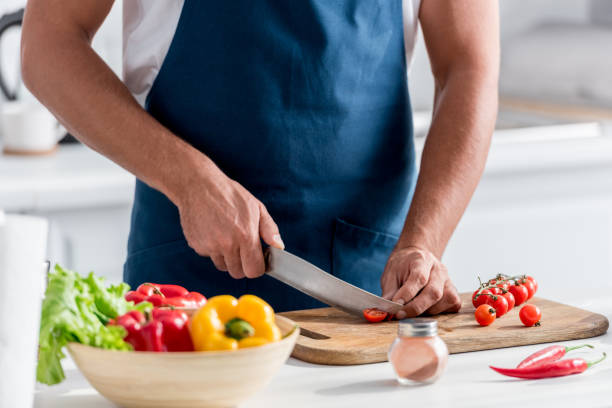 istock partial view of man cutting cherry tomatoes on chopping board 1067886046