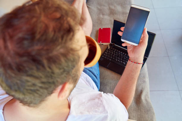 istock Man using cellphone and laptop while drinking coffee / tea on the porch. 1067888718
