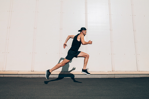 Runner man running fast in industrial city background. Sport, athletics, fitness, jogging activity