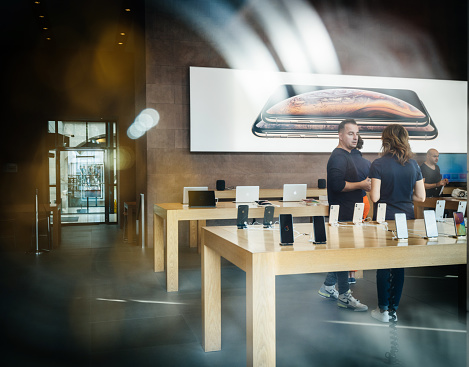 STRASBOURG, FRANCE - SEP 21, 2018:  View from the street of Apple Store with customers people buying inside admiring the new latest iPhone Xs and Xs Max pre order for Xr and Watch Series 4 wearable - street view from queue