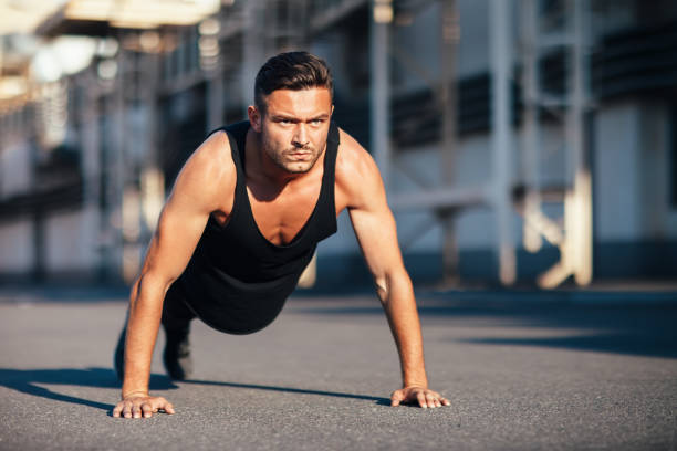 istock Young serious man doing pushups outdoor on industrial background 1067891916