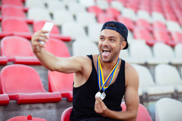 gewinner mit medaillen machen selfie zunge zeigen - humor athlete trophy one person stock-fotos und bilder