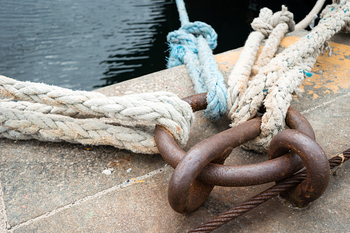 Mooring ropes attached to bitt and blue water of sea.